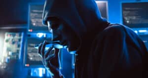 a hacker wearing a mask to cover his face is using computer to h